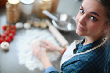 Beautiful woman cooking cake in kitchen standing near desk