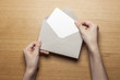 © dohee - woman hand hold a envelope and letter on the wood table.