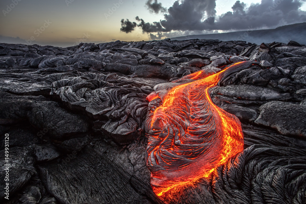 Red Orange vibrant Molten Lava flowing onto grey lavafield and glossy rocky land near hawaiian volcano with vog on background - obrazy, fototapety, plakaty 