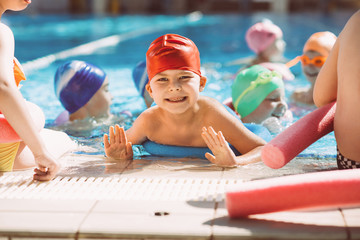 Wall Mural - happy children kids group at swimming pool class learning to swim