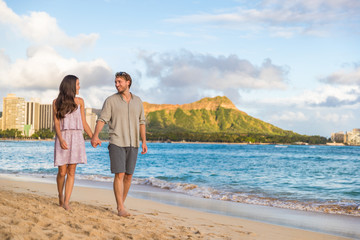 Wall Mural - Couple walking on Waikiki beach Hawaii vacation. Happy couple in love relaxing at sunset on tourist famous travel destination in Honolulu, Oahu, Hawaii.