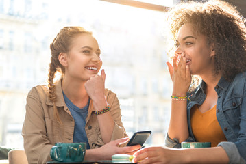 Outgoing female friends making conversation in cafe