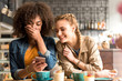 © Yakobchuk Olena - Cheerful women speaking at table in cafe