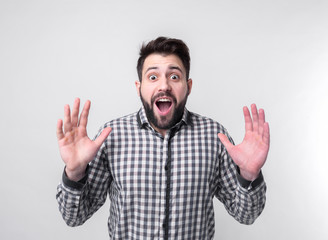 Young man with arms raised. Guy spread hands out. Isolated on white background. Bearded student wearing a white shirt arms opened looking up.