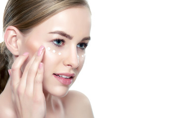 Wall Mural - beautiful young blond woman applying face cream under her eyes. facial treatment. cosmetology, beaut