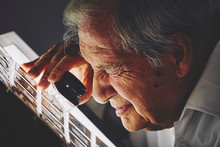 Senior Man Looking At Sheet Of Film Slides With Magnifier