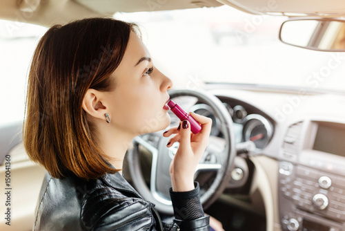 Fotomural Businesswoman looking in rear view mirror and putting make up in car