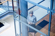 © Connect Images - High angle view of businesswoman looking at smartphone on office stairway