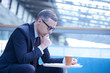 © Connect Images - Businessman on sofa reading paperwork in office atrium