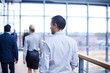 © Connect Images - Rear view of businessmen and woman walking on office balcony