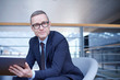 © Connect Images - Portrait of confident businessman holding laptop on office balcony