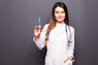 © F8  \ Suport Ukraine - Young doctor woman with syringe on grey background