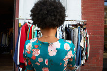 Rear View Of Young Female Fashion Blogger With Afro Hair Looking At Vintage Clothes Rail, New York, USA