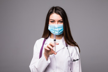 Doctor or nurse in face mask and lab coat holding syringe. Isolated over grey