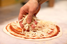 Cook Hand Pouring Cheese To Pizza At Pizzeria