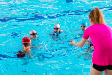 Wall Mural - happy children kids group at swimming pool class learning to swim