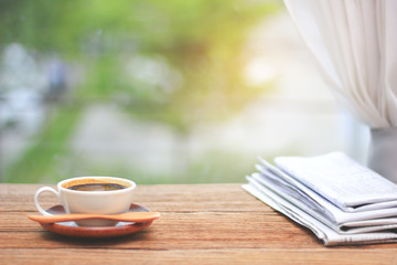 Wall Mural - Morning coffee, Cup of coffee with newspapers, near the window.background in the morning sunlight.