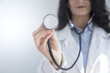 Close up of female doctor in white gown with stethoscope, focus on stethoscope. White background.