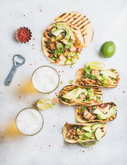 Wall Mural - Healthy corn tortillas with grilled chicken, avocado, fresh salsa, limes, beer in glasses over light grey marble background, top view. Healthy food, gluten-free, weight loss, allergy-friendly concept