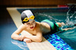 © Iryna - Sporty cute little boy lying on the stomach by the edge of swimming pool and splashing