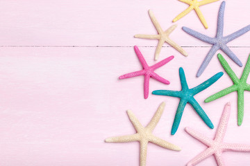 Poster - Colorful starfishes on pink wooden background