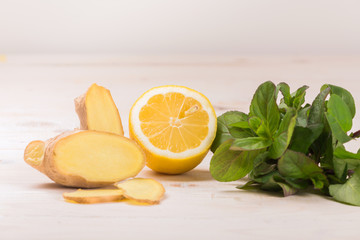 Wall Mural - Ingredients for ginger lemonade: lemon, ginger, mint on a white wooden background. Detox water. Cleaning the body of toxins, vitamins