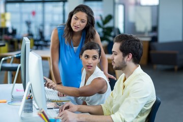 Wall Mural - Graphic designers interacting while working on personal computer