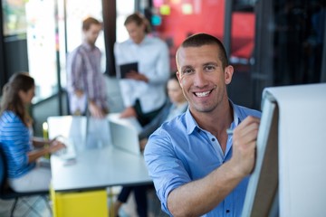 Wall Mural - Portrait of businessman writing on flip chart