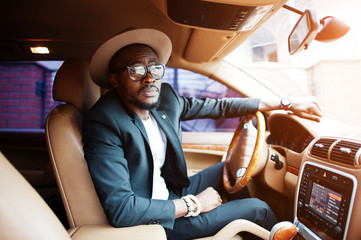 Stylish black man sitting behind the wheel of luxury car. Rich african american businessman.