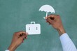 Man protecting paper cut out briefcase with umbrella