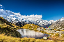 Hiking Travel Nature Hikers In New Zealand. Couple People Walking On Sealy Tarns Hike Trail Route With Mount Cook Landscape, Famous Tourist Attraction.
