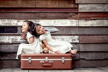 Children Two Cute Asian Little Girls Are Sitting On Suitcase And Playing Together On Wooden Background In Vintage Retro Style