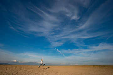 Happy woman running and jumping against blue sky