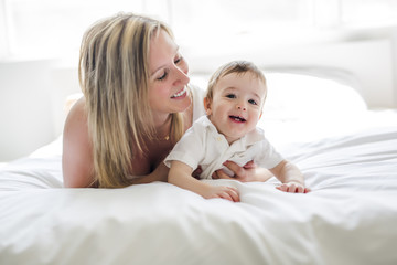 Beautiful young mother and son lying together on a bed