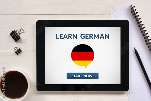 Fotografía Learn german concept on tablet screen with office objects on white wooden table
