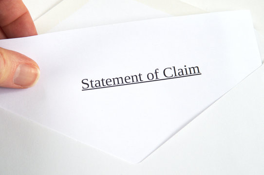 Statement of Claim printed on white paper and envelope, hand holding it, white background