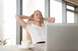 © fizkes - Businesswoman takes minute break for coffee and leaning back in chair with hands behind head. Successful female entrepreneur relaxing with satisfaction at workplace. Pleasure from great job done