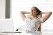 © fizkes - Cheerful businesswoman dreaming at workplace. Smiling girl leaning back in chair with hands behind head and closed eyes. Female office worker takes break after job done. Business lady relaxing at work