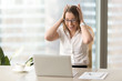 © fizkes - Exited businesswoman at desk holding had in hands and yelling while looking on laptop screen. Woman gets incredibly pleasant surprise on e-mail. Shocked female entrepreneur goes crazy because of news