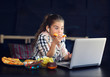© dinaphoto - 8 year old girl with unhealthy food and computer: lemonade, pizza, candy and chips, unhealthy concept.