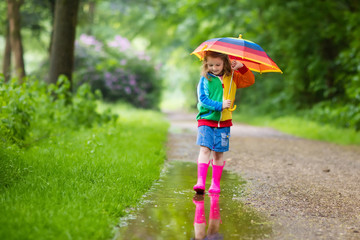 Wall Mural - Child playing in the rain with umbrella