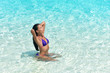 © Maridav - Beach sexy woman in bikini swimming in perfect crystalline blue water ocean. Beautiful Asian girl sun tanning and relaxing in tropical sea taking care of her hair and skin.