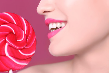 Poster - Face of beautiful young woman with lollipop on color background, closeup