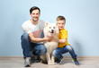 © Africa Studio - Handsome man, his son and dog near color wall