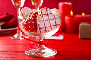 Wall Mural - Glass vase with heart shaped glazed cookies on red wooden background