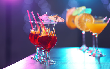 Poster - Glasses with tasty cocktails on bar counter against blurred background