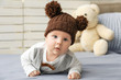 Cute little baby in funny hat lying on soft blanket