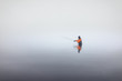 Angler in Wathose beim Auswerfen der Angelrute bei Nebel an der Küste im Wasser im Winter