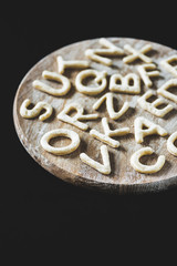 Wall Mural - close up view of letters made from cookie dough on wooden board with flour isolated on black