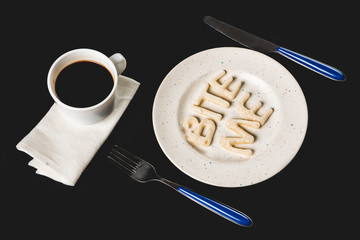 Wall Mural - top view of lettering bite me made from cookie dough on plate with coffee cup isolated on black